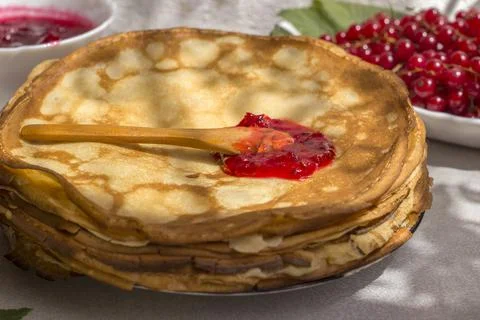 Spoon with red currant jam on a thin pancake. Traditional Russian food Stock Photos