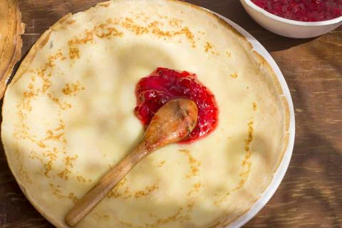 Spoon with red currant jam on a thin pancake. Stock Photos