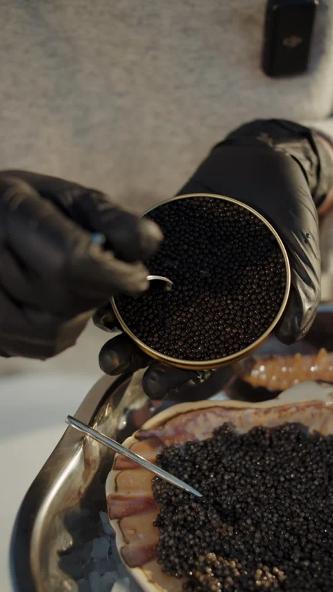 Spoon scooping black caviar from tin above scallop shell Stock Footage 309568628