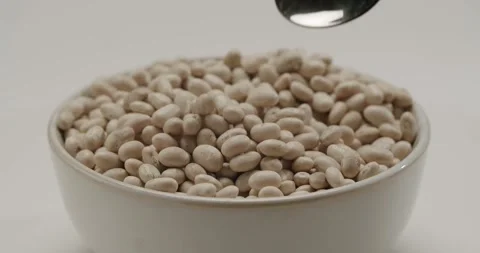 Spoon scooping dry white beans from a bowl in slow motion Stock Footage 344321044