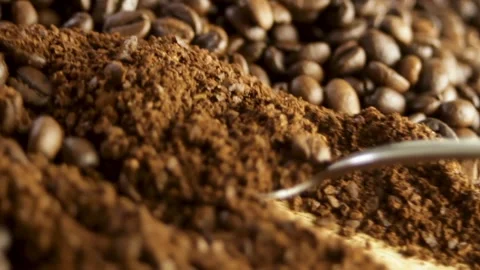 Spoon scooping up ground coffee against a close-up of coffee beans Stock Footage 316089487