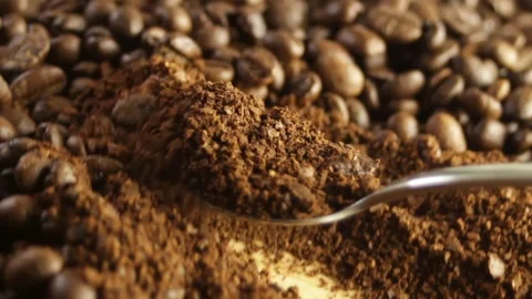 Spoon scooping up ground coffee against a close-up of coffee beans Stock Footage 316089568