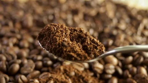 Spoon scooping up ground coffee against a close-up of coffee beans Stock Footage 316089752