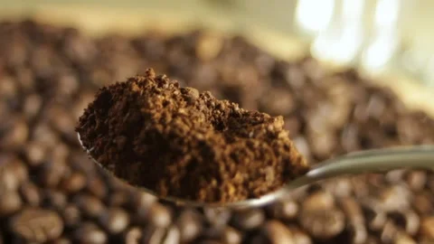 Spoon scooping up ground coffee against a close-up of coffee beans Stock Footage 316089827