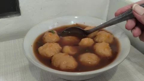 Spoon scooping savory bakso meatball from traditional Indonesian soup Stock Footage 321384403