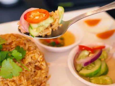 Spoon scooping Thai stir fried rice, with chili and cucumber Foto stock