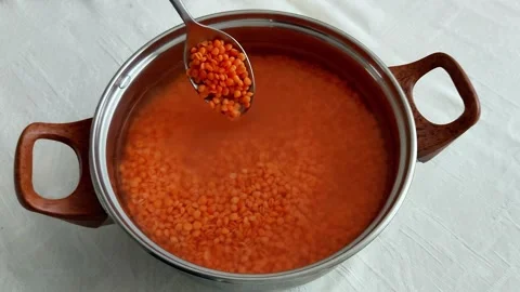 Spoon Scoops Red Lentils from Pot on White Textured Tablecloth Surface Vídeos de archivo 326653787