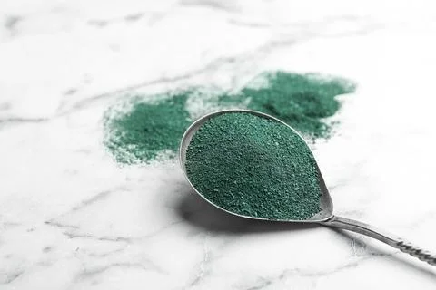 Spoon of spirulina algae powder on marble background Foto stock