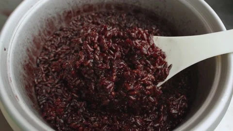 Spoon stir cooked red or black Thai organic rice in a rice cooker bowl close up. Stock Footage 236546485