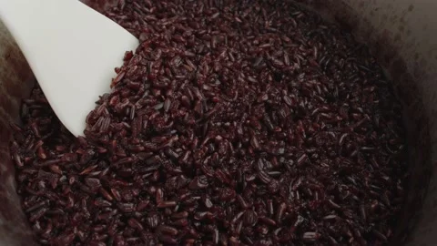 Spoon stir cooked red or black Thai organic rice in a rice cooker bowl close up. Stock Footage 236546497