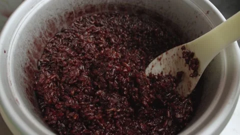 Spoon stir cooked red or black Thai organic rice in a rice cooker bowl close up. Stock Footage 236546514