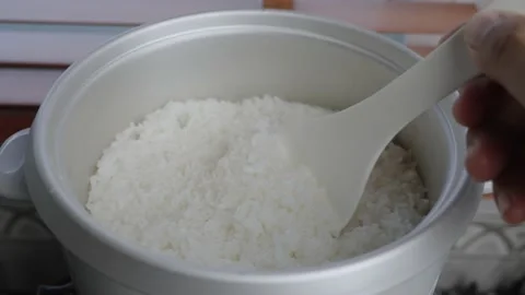 Spoon stir cooked white Thai jasmine rice in a rice cooker bowl Stock Footage 232915245