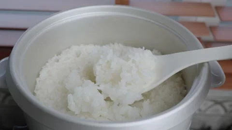 Spoon stir cooked white Thai jasmine rice in a rice cooker bowl Stock Footage 232915250