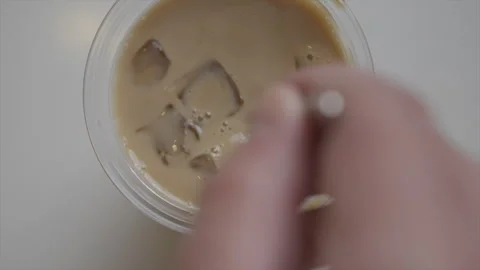 A spoon is stirring a cup of coffee with ice cubes in it Stock Footage 301621468