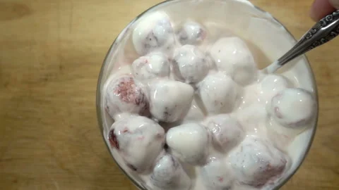 Spoon stirs strawberries and cream in slow motion Stock Footage 133394853