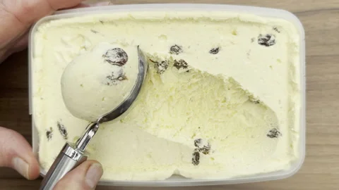 A spoon tool scooping out the first rum and raisin ice cream from a tub. Stock Footage 304342963