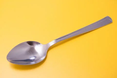 Spoon on a yellow background Stock Photos