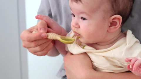 A spoonful of broccoli puree - the first taste Stock-Footage 329860311