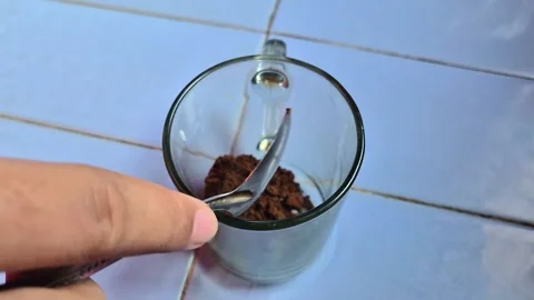 A spoonful of ground black coffee is poured into a glass Stock Footage 337905860