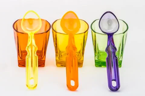 Spoons and colored glasses Stock Photos