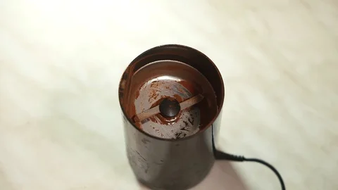 Spoons coffee beans into a coffee grinder. Видео 102894882