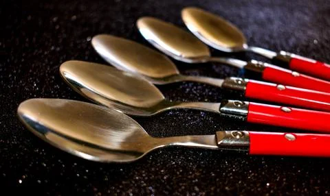 Spoons in row on black background Stock Photos