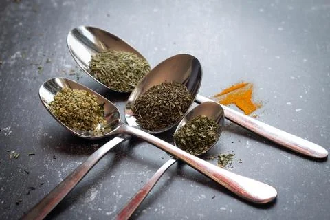 Spoons with spices and herbs on a black background. Food and cuisine ingredients Stock Photos