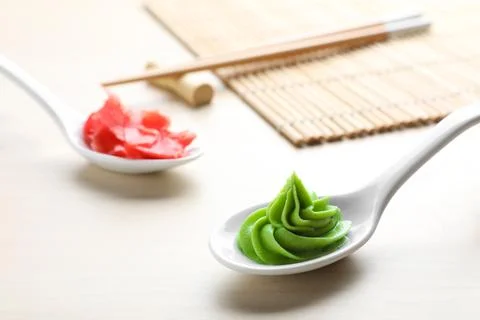 Spoons with swirl of wasabi paste and pickled ginger on white table, closeup Stock Photos