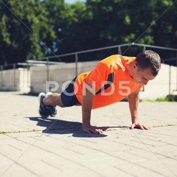 Sport, fitness and workout concept - sportsman doing push-ups exercise outdoo Stock Photos