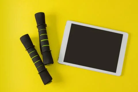 Sport flat lay composition tablet and black dumbbells Stock Photos