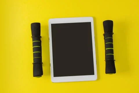 Sport flat lay composition tablet and black dumbbells Stock Photos