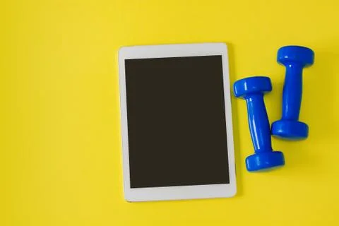 Sport flat lay composition tablet and blue dumbbells Stock Photos