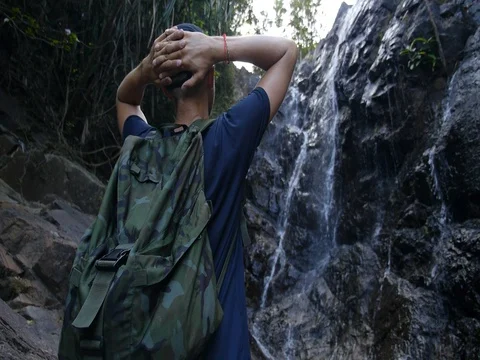 Sport Hiker Man With Backpack Looking At Waterfall After Climbing Видео 77094848