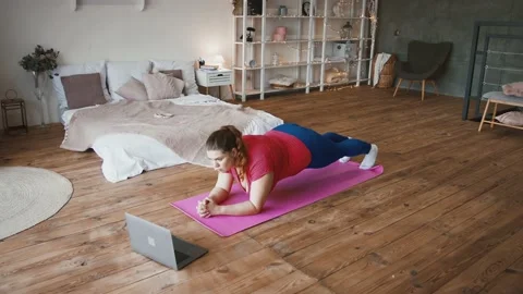 Sport tutorial. Young overweight lady doing plank exercise, watching online Stockbeeldmateriaal 143566406