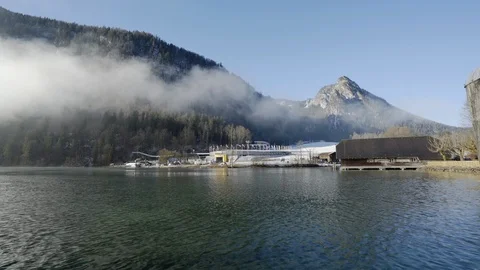 Sporting arena in Alps with clouds in mountains next to lake on sunny day Stock Footage 121753204