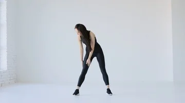 The sportive athletic trainer is warming up. She is stretching her body by Stock Footage 85570760