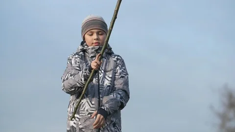 Sportive boy in spring jacket turning a long stick around outdoors in spring in Stock Footage 105185976