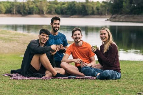 Sportive people facing the camera while drinking tea sitting on a park Stock Photos