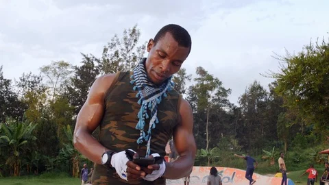 A sportive young man using a cell phone in the park while standing on the Vídeo Stock 110884518