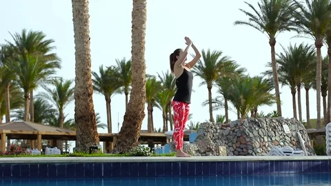 Sports girl doing basic exercises from yoga standing on the edge of the blue 库存影片 74751255