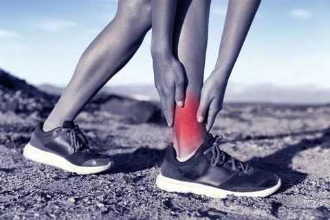 Sports injury - woman runner on trail running holding painful ankle in pain Stock Photos
