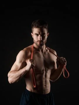 Sports man with a beard on a black background with gymnastic elastic bands in Stock Photos