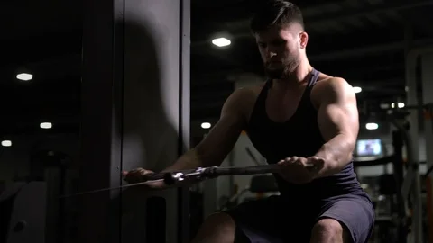 Sports man sitting doing pulldowns, developing upper-back, exhausted workout Stock Footage 121804789