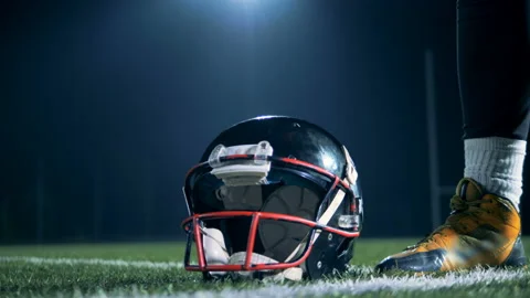 Sportsman, american football player picks up a helmet from a grass at a stadium. Stock Footage