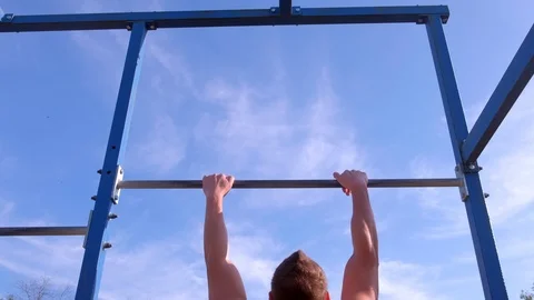 Sportsman bodybuilder making pull ups on horizontal bar in city park, back view. Vídeo Stock 120551708