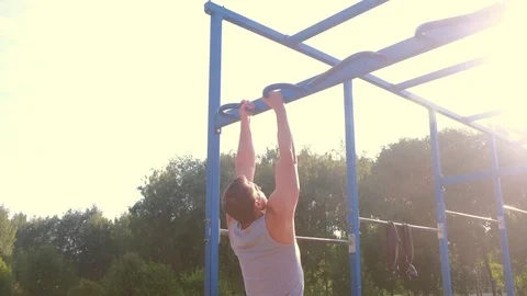 Sportsman bodybuilder making pull ups on bar in city park, camera in motion. Vídeo Stock 123362258