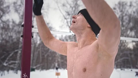 Sportsman do L sit pull up on bar. Cold winter training. Man workout outdoor gym 動画素材 262294057