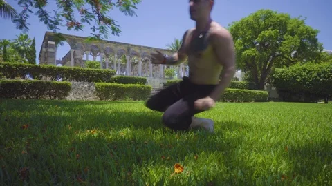 Sportsman makes a sequence of exercises with flips and movement on grass Stock Footage 112696552
