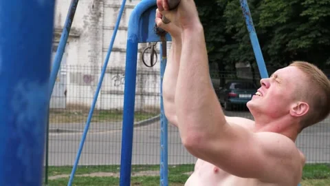Sportsman performing intense pull-up workout on blue exercise equipment Video stock 321053419