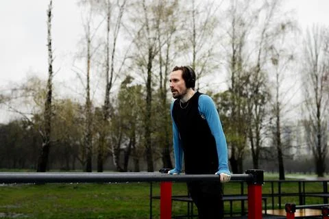 Sportsman sets a record for pushups parallel bars. Concentrated man listen Stock Photos
